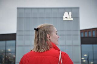 A young woman in front of an Aalto University building
